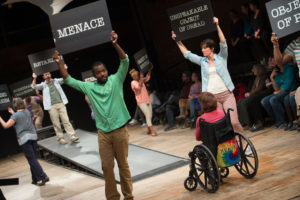 Actors rehearsing play, holding protest signs